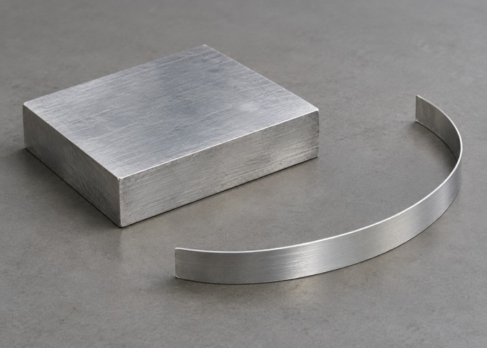 Thick metal block beside a separate thin curved strip