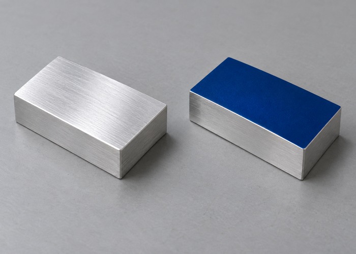 Two metal blocks with bare and blue-coated top surfaces