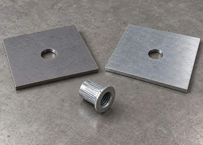 Two steel sheet coupons with round holes beside a separate rivet nut