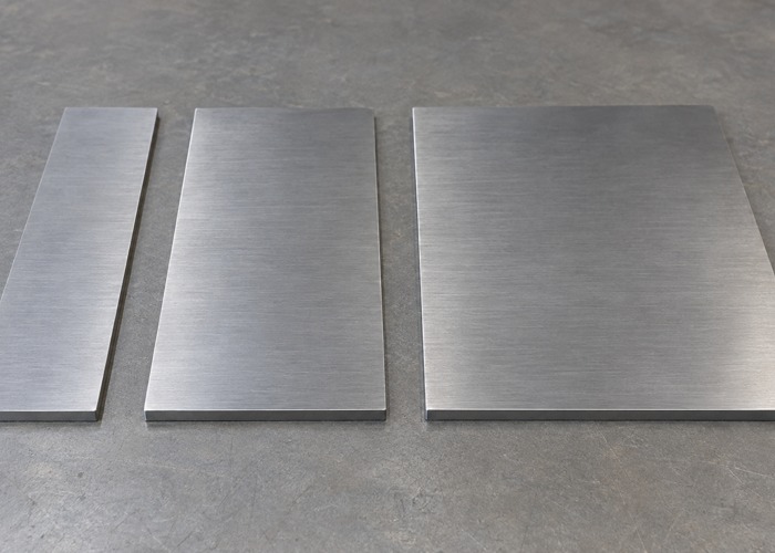 Three separate rectangular metal blanks with visible edges
