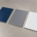 Three separate coated metal sample panels in blue gray and white